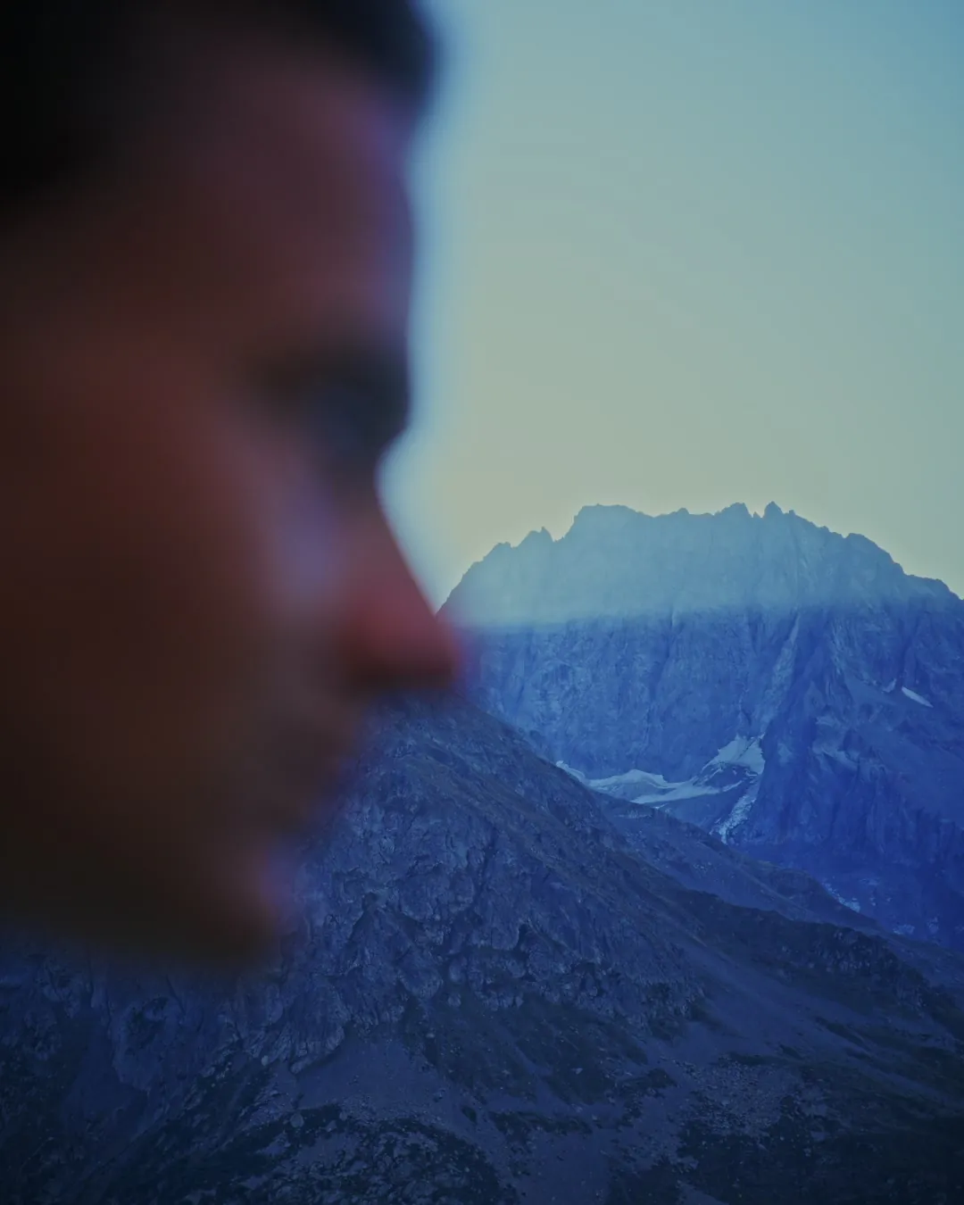 Le profil de Paul, flou au premier plan, devant un sommet de montagne net.
